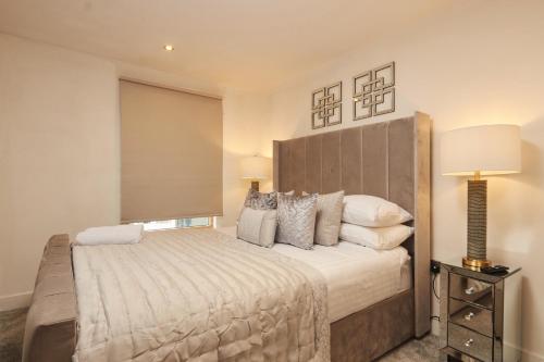 a bedroom with a large bed and a lamp at Deluxe City Apt Riverside Balcony &Free Parking in Leeds