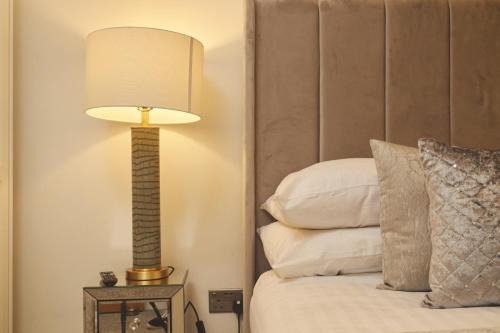 a lamp sitting on a table next to a bed at Deluxe City Apt Riverside Balcony &Free Parking in Leeds