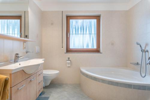 a bathroom with a tub and a toilet and a sink at Huterhof Apt Tatschblick in Riobianco