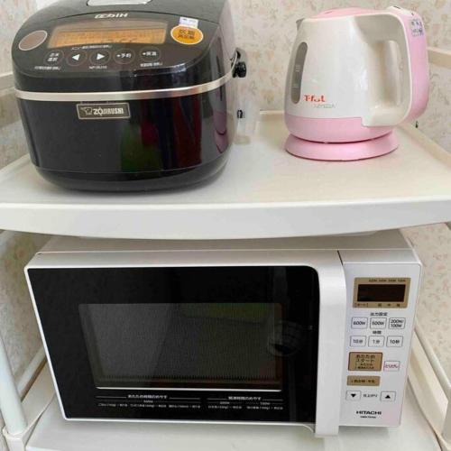 a microwave and a toaster on a shelf at Amitie Villa in Hannan