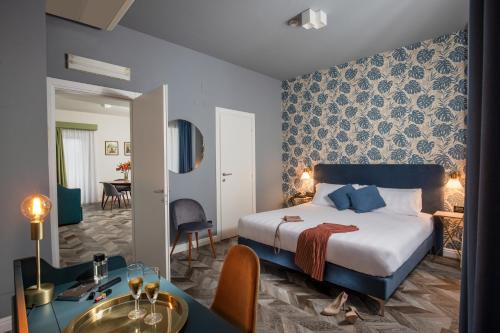 ローマにあるBloom Hotel Romeのベッドとダイニングルームが備わるホテルルームです。