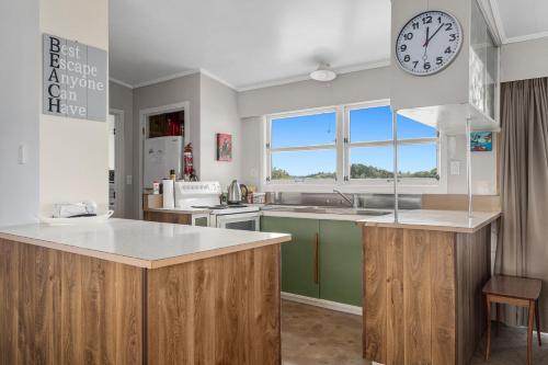 a kitchen with a large clock on the wall at Habourside - Ohope Holiday Home in Ohope Beach