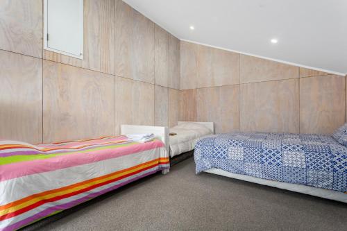 een slaapkamer met 2 bedden en een muur bij Habourside - Ohope Holiday Home in Ohope Beach