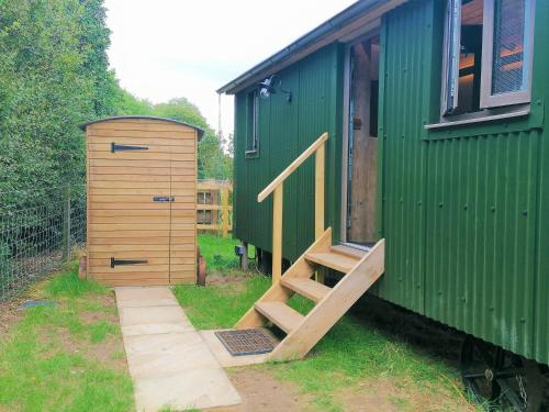 a green train car with a door and a wooden ramp at The Huddle at Big Sky Brisley in Brisley