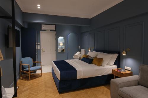 een slaapkamer met een bed, een stoel en een bank bij K23 Color Suites in Athene