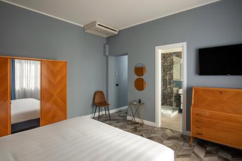 a bedroom with a bed and a dresser and a tv at Bloom Hotel Rome in Rome