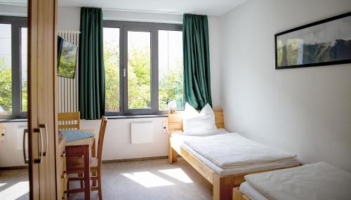 a room with two beds and a table and windows at Hotel Garni Fischerfleck in Ismaning near Munich in Ismaning