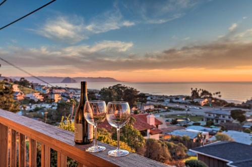 a bottle of wine and two wine glasses on a balcony at Pet-Friendly Cayucos Home with Ocean Views! in Cayucos