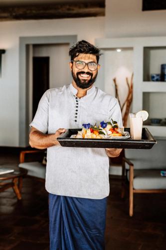 a man holding a tray with food on it at Saltasia Boutique Beach Villa in Mirissa