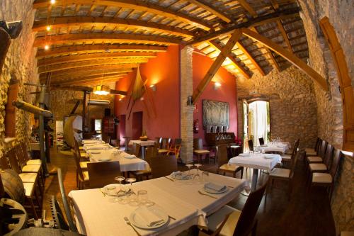a restaurant with white tables and chairs in a building at Mas Masdeu in L'Aldea