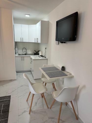 a kitchen with a table and two chairs and a tv on a wall at Lena 2 in Jajce