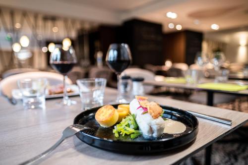 a plate of food on a table with wine glasses at Mercure Grenoble Meylan in Meylan