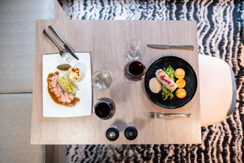 a wooden table with a plate of food and glasses of wine at Mercure Grenoble Meylan in Meylan