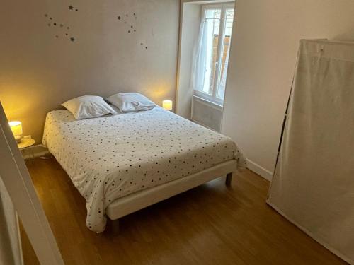 a small bedroom with a bed with two pillows and a window at L'eutopia au cœur de Chablis, parking gratuit in Chablis