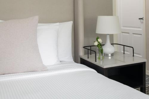 a white bed with a table with a lamp and flowers at Toll House Hotel Los Gatos in Los Gatos