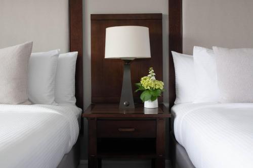 a bedroom with two beds and a table with a lamp at Toll House Hotel Los Gatos in Los Gatos