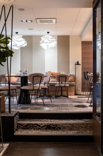 a dining room with tables and chairs and lights at Mercure Grenoble Meylan in Meylan