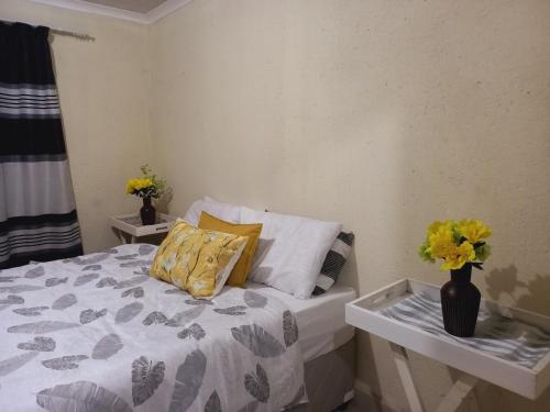 a bedroom with a bed with a vase of flowers on it at Tangwe Guest House 