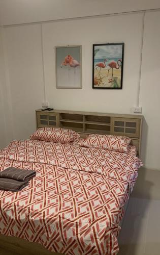 a bed in a bedroom with two pictures on the wall at Barzilla Bar And Guesthouse in Pattaya