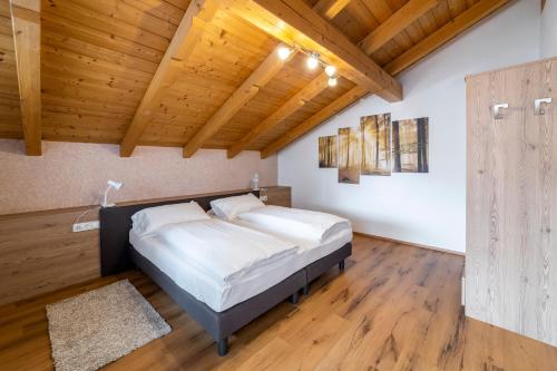 um quarto com uma cama e um tecto de madeira em Apartments Gasser em Rasun di Sopra