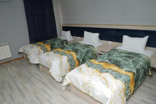 a room with three beds with green and white blankets at RamRamay in Qax