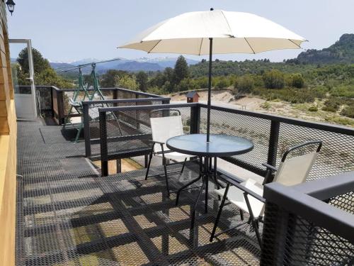 una mesa y sillas en un balcón con sombrilla en Apart Hotel Pehuenia en Villa Pehuenia