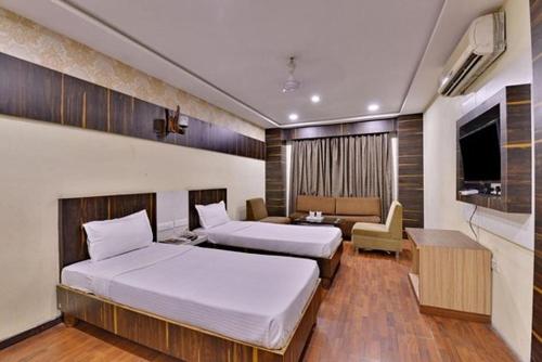 Habitación de hotel con 2 camas y sala de estar. en hotel puneet international en Raipur