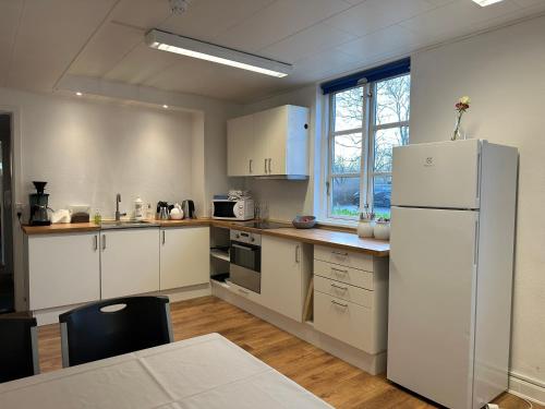 a kitchen with white cabinets and a white refrigerator at Tune Kursuscenter in Greve