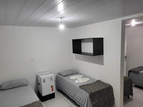 a small room with two beds and a television at Hotel Veneza in Garanhuns