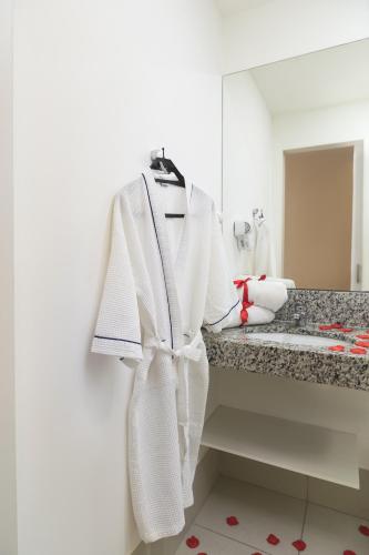 a bathroom with a white robe hanging on a sink at Tulip Inn Vila Velha in Vila Velha