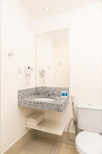 a bathroom with a sink and a toilet at Tulip Inn Vila Velha in Vila Velha
