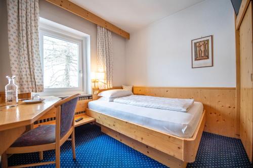 1 dormitorio con cama, escritorio y mesa en Garni Bondi, en Selva di Val Gardena