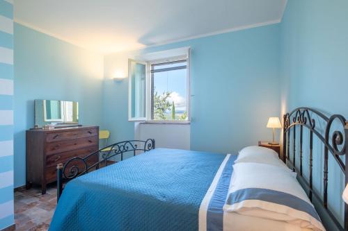 ein blaues Schlafzimmer mit einem Bett und einem Fenster in der Unterkunft Casale Stabbiatelli by VacaVilla in Montenero