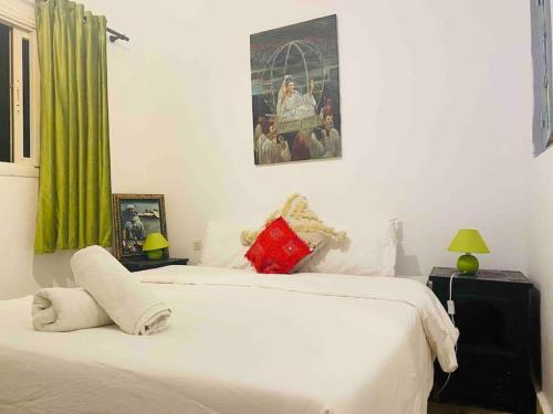 ein Schlafzimmer mit einem weißen Bett und einem Gemälde an der Wand in der Unterkunft Jolie petit Riyad avec piscine belle terrasse wifi in Marrakesch