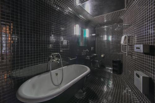 ein schwarz gefliestes Bad mit einer Badewanne und einem Waschbecken in der Unterkunft Au Coeur de Saint Germain des près (Montana3) in Paris