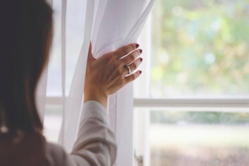 a woman opening a window with her hand at Szidónia Castle in Röjtökmuzsaj