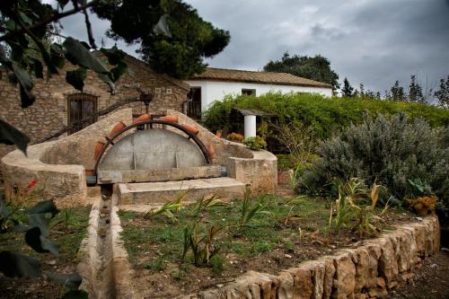 a stone bench in a garden in front of a house at Mas Masdeu in L'Aldea