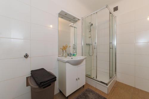 y baño blanco con lavabo y ducha. en Cosy brand new Apartment en Viena