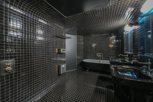 La salle de bains noire est pourvue d'une baignoire et d'un lavabo. dans l'établissement Magic suite in Saint Germain des Près (Montana5), à Paris