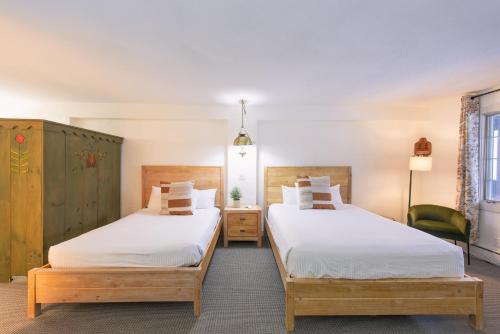 a bedroom with two beds and a chair at Innsbruck Inn at Stowe in Stowe