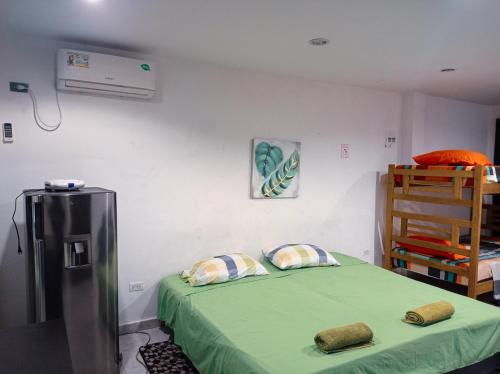 a bedroom with a green bed and a refrigerator at Posada Miss Gloría in San Andrés