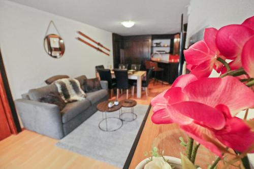 a living room with a couch and a table with pink flowers at Magnifique appartement centré in Crans-Montana