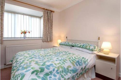 a bedroom with a bed and two lamps and a window at Aderyn Du in Abergele