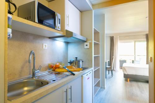 a kitchen with a sink and a microwave at Zenitude Hôtel-Résidences Le Cannet in Le Cannet