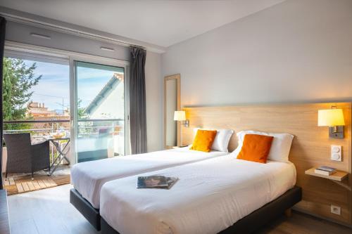 a hotel room with two beds and a large window at Zenitude Hôtel-Résidences Le Cannet in Le Cannet