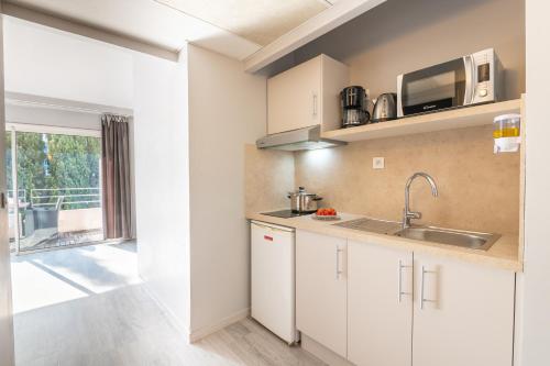 a kitchen with white cabinets and a sink and a window at Zenitude Hôtel-Résidences Le Cannet in Le Cannet