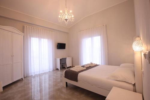 a white bedroom with a bed and a chandelier at B&B Royal in Sellia Marina