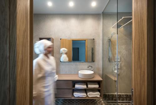 eine Frau, die in ein Badezimmer mit Waschbecken und Dusche geht in der Unterkunft HERMIONE 3-Bedroom Villa in Agios Nikolaos in Agios Nikolaos