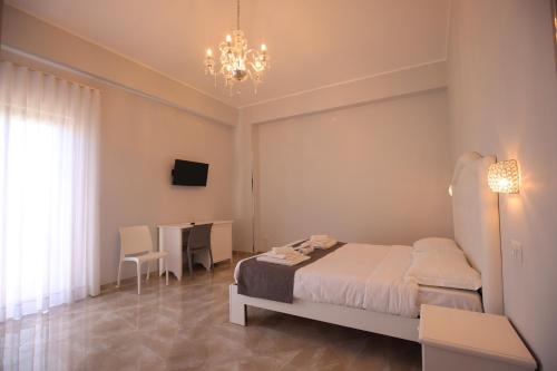 a bedroom with a bed and a table and a chandelier at B&B Royal in Sellia Marina
