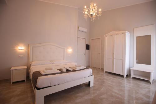 Habitación blanca con cama y lámpara de araña. en B&B Royal, en Sellia Marina